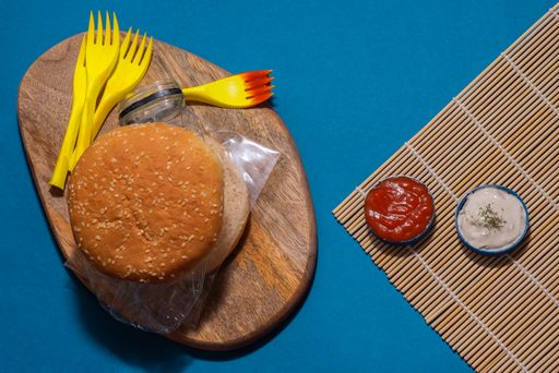 A top view of a burger with a crinkled-up plastic bottle in it - plastic waste concept