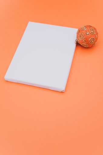 Elegant orange silver Christmas decorations and painting canvas with sapce for text on a orange tabletop surface