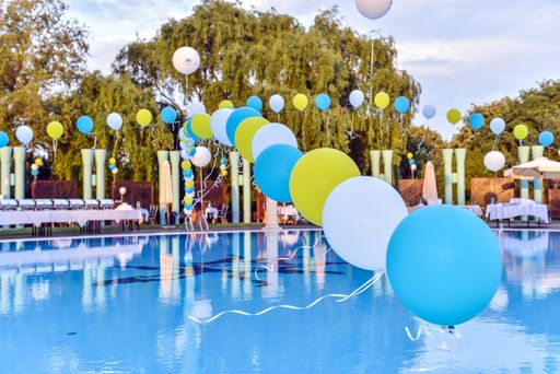 A beautiful view of different colored balloons aligned and hung on the water pool under a blue sky