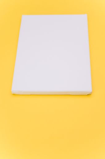 top view shot of blank white paint canvas on a yellow paper surface with copy space