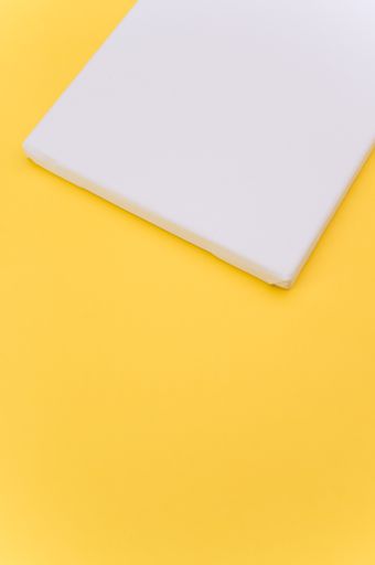 top view shot of blank white paint canvas on a yellow paper surface with copy space