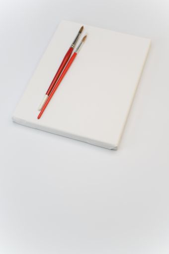 top view shot of blank white paint canvas and tools on a white paper surface with copy space