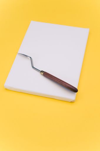 top view shot of blank white paint canvas and tools on a yellow paper surface with copy space