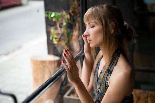 A portrait of a sad Serbian woman longingly looking out of the window