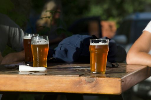 The friends drinking a pint of beer over wooden table, craft beer, three glasses, relaxed lifestyle