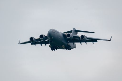 A flying military aircraft against a cloudy sky