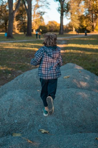 A blonde kid running on the riverside in spring