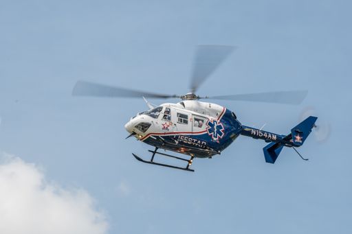 A flying N124AM helicopter against a clear blue sky