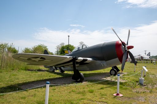 A vintage military aircraft displayed in an airbase during a sunny day