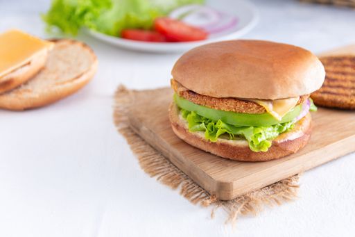 A closeup shot of a hamburger on a wooden cutting desk