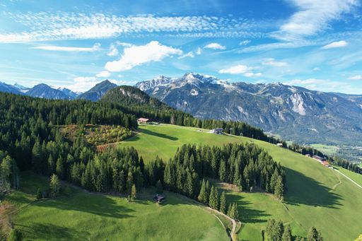 Drone view of a beautiful mountain landscape with blue sky and snow covered tops. Austrian Alps, alpine meadows and coniferous forest at autumn.