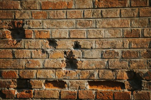 A closeup of an old aged brick wall texture with bricks missing from it
