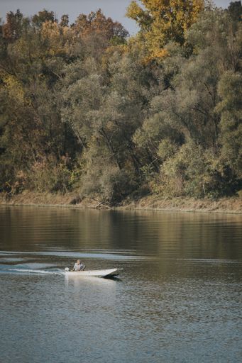 A vertical shot of a man driving a boat on the water in Brcko, Bosnia and Herzegovina