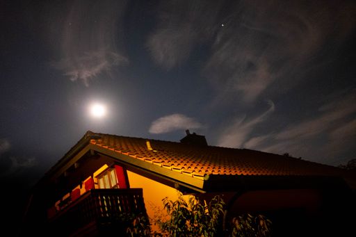 A low angle shot of a building under a cloudy sky with moonlight