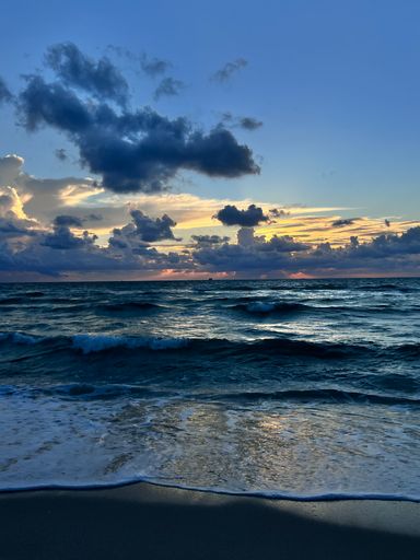 A vertical shot of the sea under a beautiful cloudy sky at sunrise