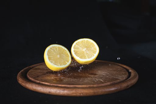 A just cut juicy lemon on a cutting wooden board on a dark background - food photography