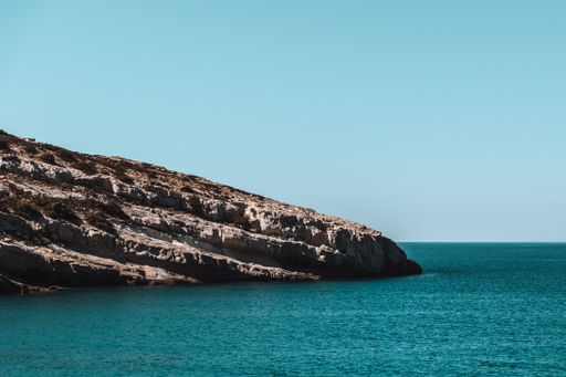 A Matala caves surrounded with calm sea under the clear blue sky in Greece - perfect for background