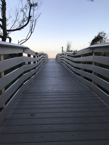 A vertical shot of a beach boardwalk on a sunny day