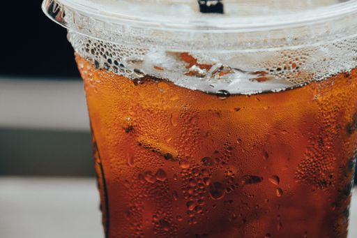A close-up shot of a plastic cup of iced tea with ice cubes inside.