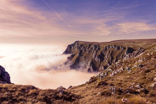 A mesmerizing view of a cloudy mountain with a purple cloudy sky