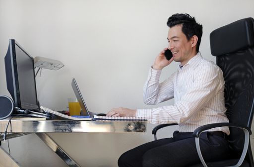An amazing shot of a young male speaking by phone on his workplace