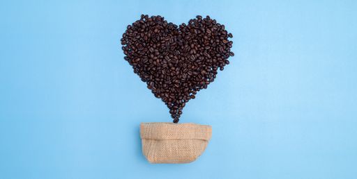 The coffee beans with a small bag on blue background. Caffeine, energy.