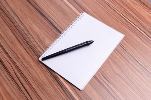 A closeup of the blank copybook with a pen on the table.
