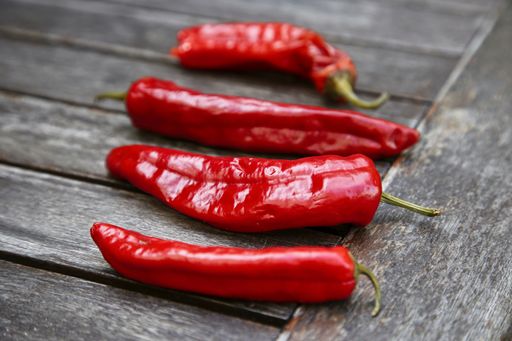 A closeup selective focus shot of red chilies on a wooden table background