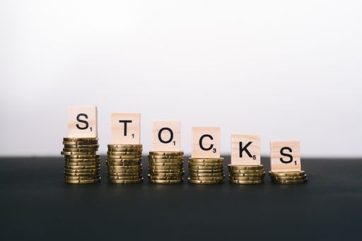 A closeup selective focus shot of a word "Stocks" on stacks of golden coins