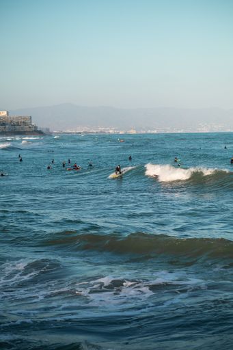 A view of many Surfers surfing in the water with a blue sky on a sunny day