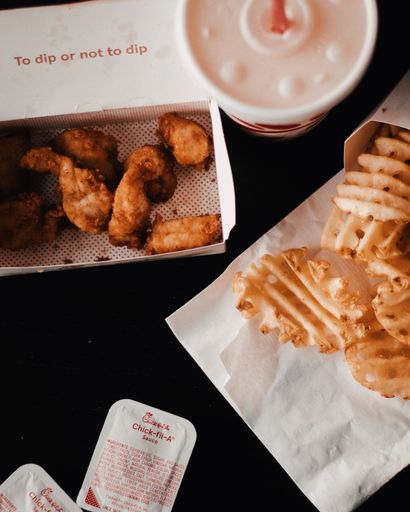 An overhead shot of deep-fried chicken and chips in boxes
