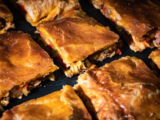 A high angle shot of some delicious Galician tuna empanada on a black tray