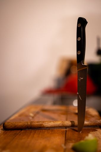 A vertical shot of a knife on a wooden cutting board