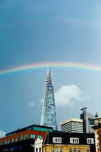 An amazing vertical shot of a cityscape with a skyscraper on a beautiful rainbow background