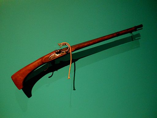 An antique old musket hanging on a green wall