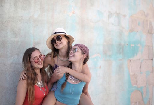 A beautiful shot of a group of female friends having fun time with accessories with a white wall as background