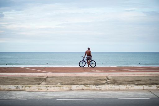 cyclist standing on the shore looking at the sea. Salvador, Bahia, Brazil.