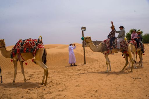 A group of tourists riding camels in Dubai, UAE