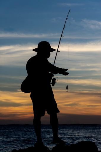 Silhouette of fishermen on the rocks at sunset. Salvador, Bahia, Brasil