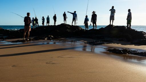 Silhouette of fishermen with their poles at sunset. Salvador, Bahia, Brasil