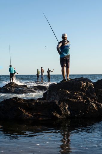 Silhouette of fishermen with their poles at sunset. Salvador, Bahia, Brasil