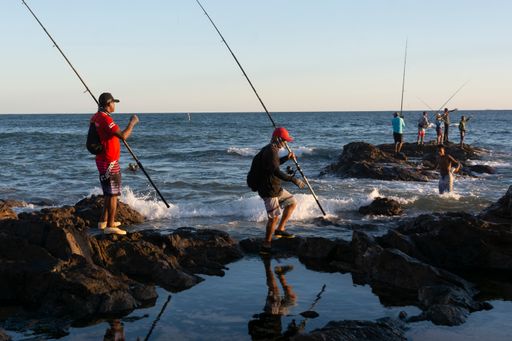 Silhouette of fishermen with their poles at sunset. Salvador, Bahia, Brasil
