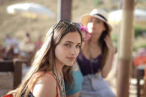A beautiful shot of two females having a fun time with sunhats and glasses with a blurry background