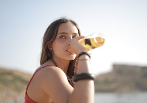 A beautiful shot of a woman with a bottle of drink with accessories with mountain and daylight as background