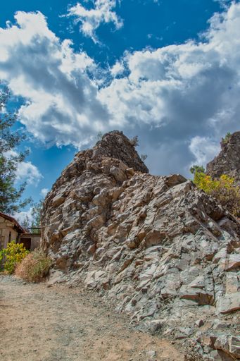 A vertical shot of a rocky area under the cloudy sky