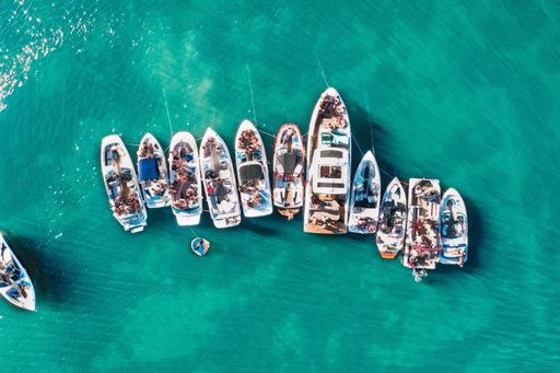 An overhead aerial drone shot of different sized boats docked close to each other near the pier