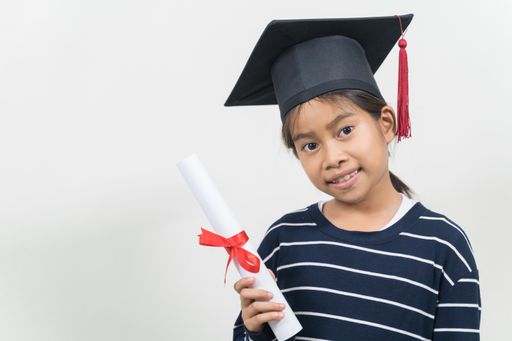 A happy Thai kid with a graduation hat and diploma isolated on white background