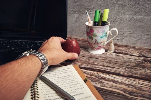 A notebook computer markers and red apple on the wooden table