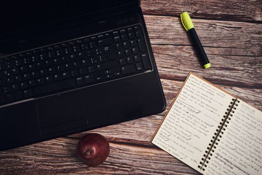 A laptop and a notebook on a wooden desk