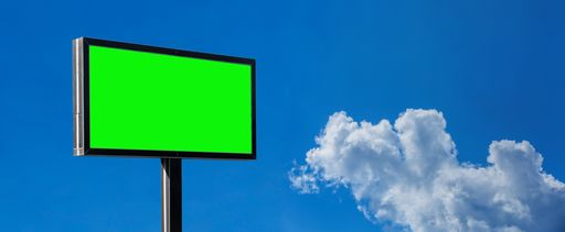 A low angle view of a billboard with green screen against a cloudy sky